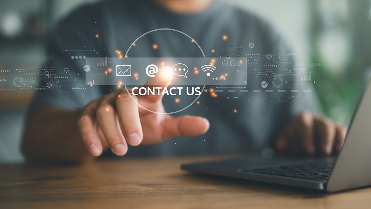 Image of a human on laptop with contact us written